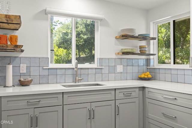 kitchen featuring backsplash, gray cabinetry, and sink