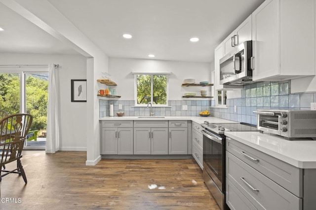 kitchen with appliances with stainless steel finishes, dark wood-type flooring, and a healthy amount of sunlight