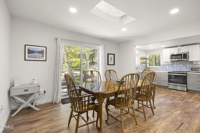 dining area featuring hardwood / wood-style floors, a skylight, and a wealth of natural light