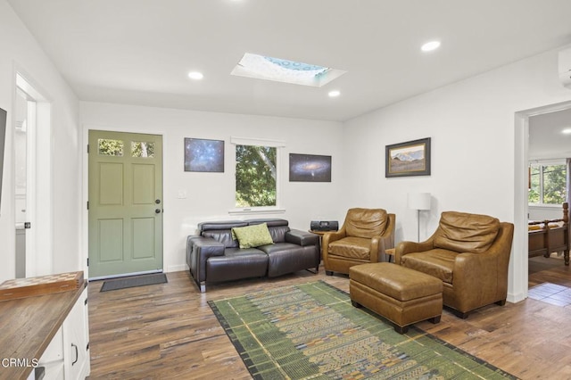 living room with dark hardwood / wood-style flooring, a wall unit AC, and a skylight