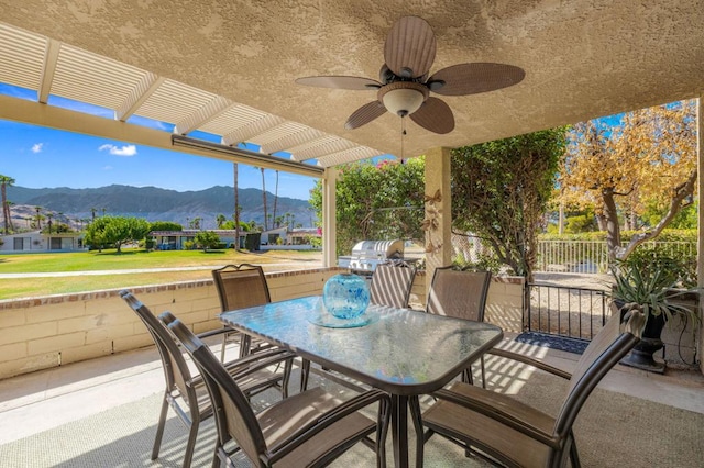 view of patio with grilling area, a pergola, ceiling fan, and a mountain view