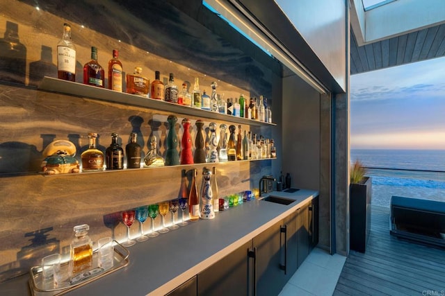 bar with a water view, sink, and light tile patterned floors