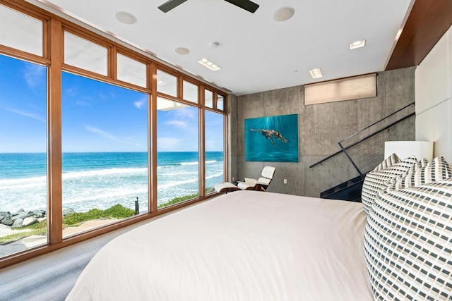 bedroom with ceiling fan, multiple windows, and a water view