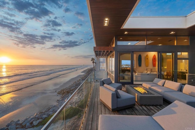 exterior space with a water view, a beach view, and an outdoor living space with a fire pit