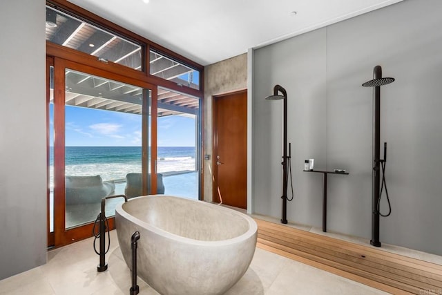 bathroom featuring a water view, a bath, and a beach view