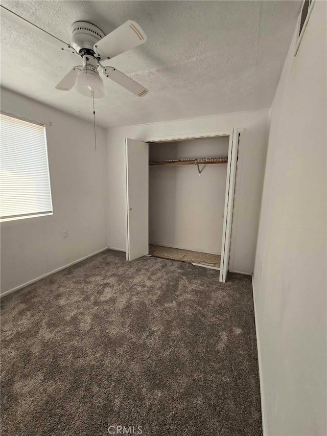 unfurnished bedroom featuring a textured ceiling, dark carpet, ceiling fan, and a closet