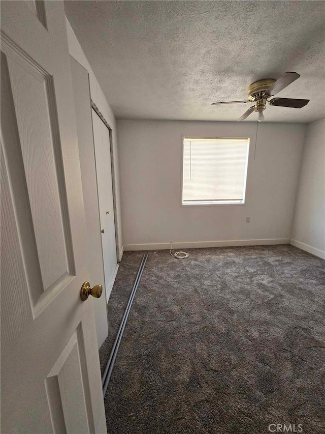 unfurnished bedroom with ceiling fan, a textured ceiling, and dark colored carpet