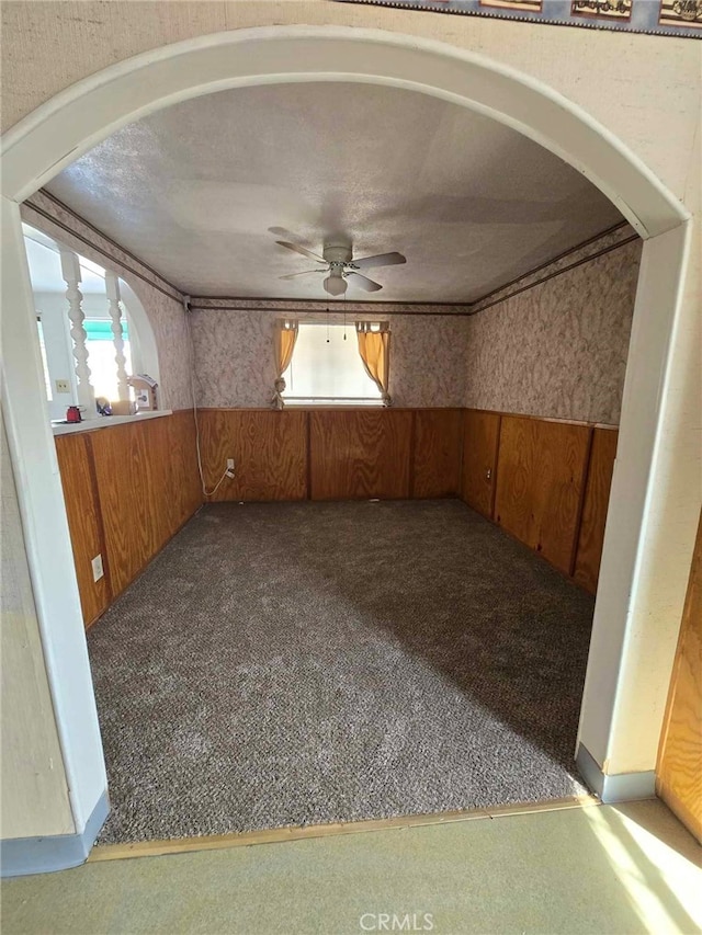 interior space featuring a textured ceiling, wood walls, and ceiling fan