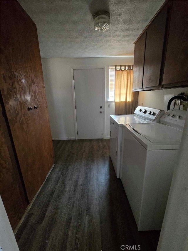 laundry area featuring a textured ceiling, washer and clothes dryer, dark wood-type flooring, and cabinets