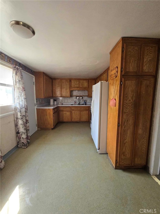 kitchen with decorative backsplash, white fridge with ice dispenser, and light colored carpet