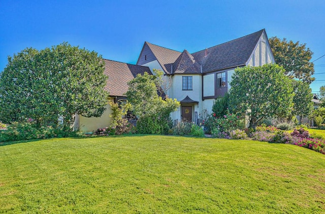 tudor-style house featuring a front lawn