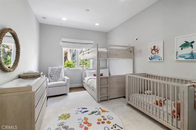 bedroom with light carpet and a nursery area