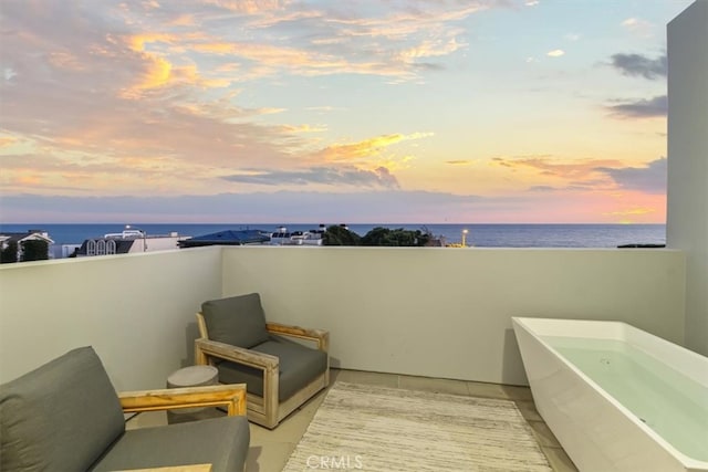 patio terrace at dusk with a balcony and a water view