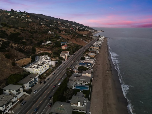 aerial view at dusk with a view of the beach and a water view