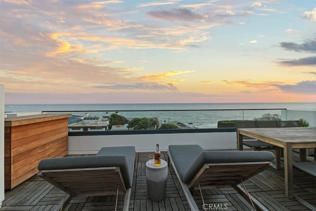 balcony at dusk featuring a water view