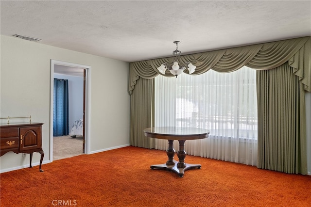 dining space with a textured ceiling, carpet flooring, and a notable chandelier