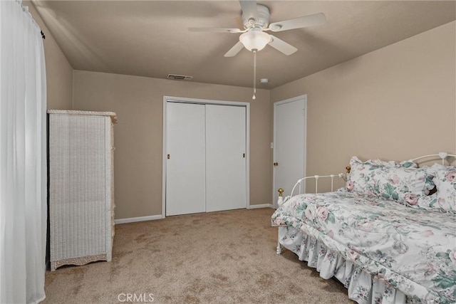 carpeted bedroom with a closet, visible vents, baseboards, and ceiling fan