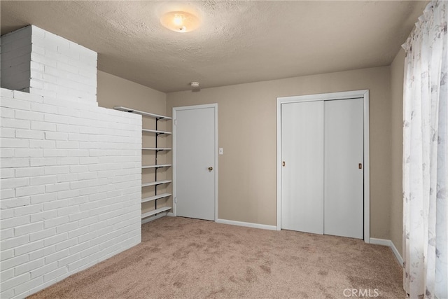 unfurnished bedroom with light carpet, a textured ceiling, and a closet