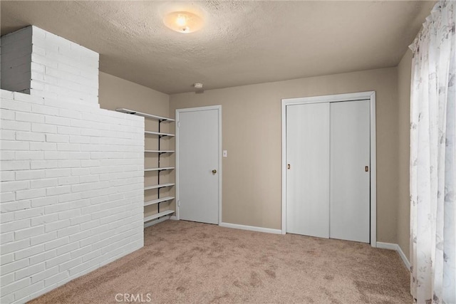unfurnished bedroom with carpet floors, a textured ceiling, baseboards, and multiple closets