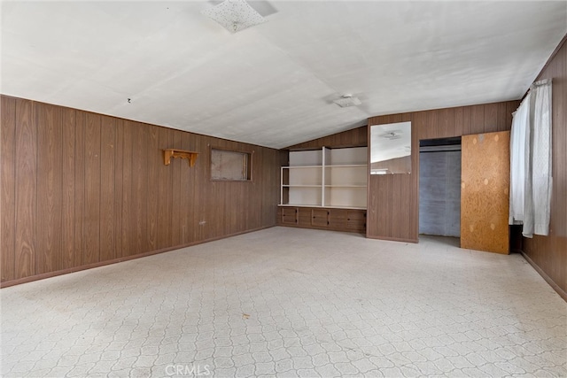 unfurnished bedroom with vaulted ceiling and wood walls