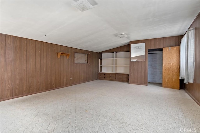unfurnished living room featuring wooden walls and vaulted ceiling