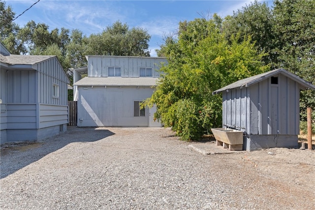 back of house with a storage unit