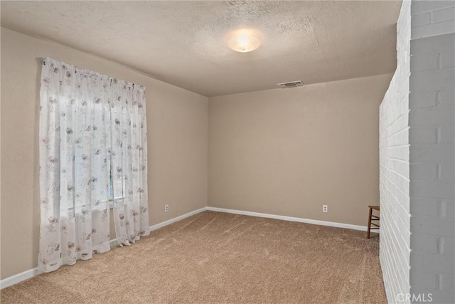 carpeted empty room with baseboards, a textured ceiling, and visible vents
