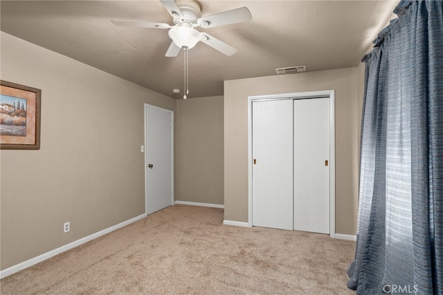 unfurnished bedroom with ceiling fan, light colored carpet, and a closet