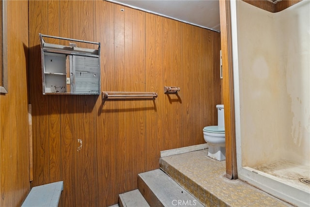 bathroom with walk in shower, wooden walls, and toilet