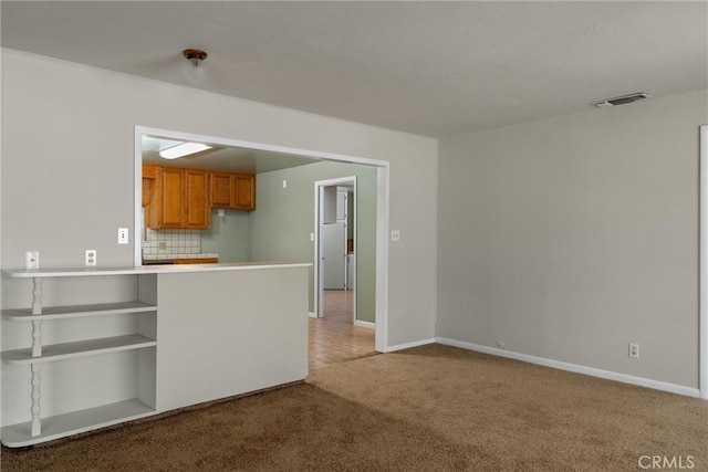 unfurnished living room with visible vents, light carpet, and baseboards