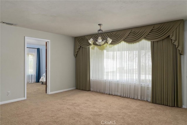 carpeted empty room featuring baseboards and visible vents
