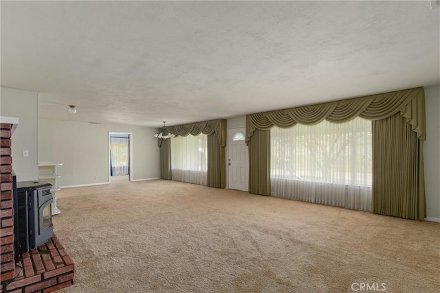 unfurnished living room featuring carpet floors, a wood stove, and baseboards
