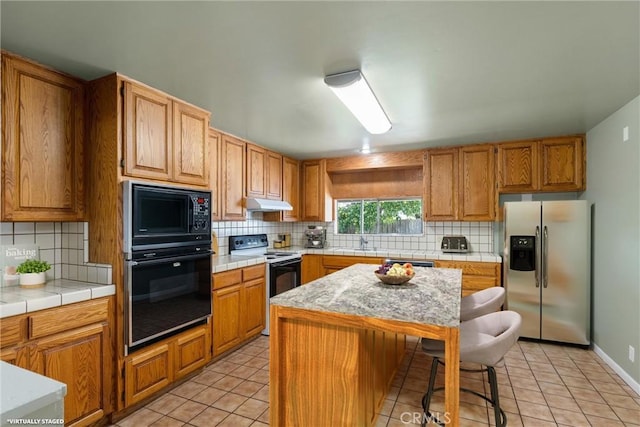kitchen featuring black appliances, backsplash, light tile patterned flooring, and a sink