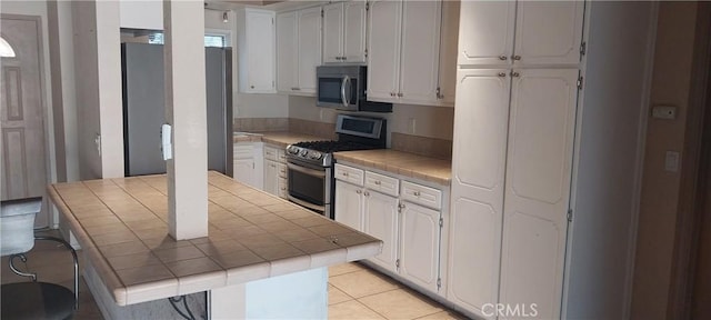 67130 Garbino Rd, Cathedral City, CA 92234 - kitchen with tile countertops, white cabinets, light tile patterned flooring, and stainless steel appliances