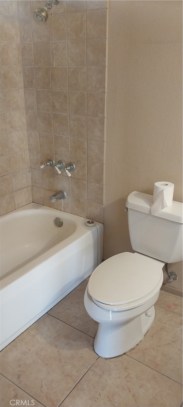 bathroom featuring tiled shower / bath combo, tile patterned flooring, and toilet