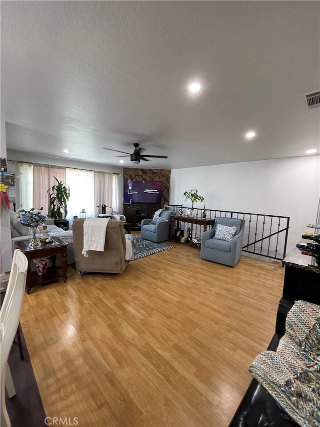 living room featuring a textured ceiling, wood-type flooring, and ceiling fan