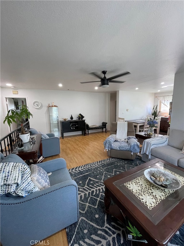 living room with ceiling fan, a textured ceiling, and hardwood / wood-style floors