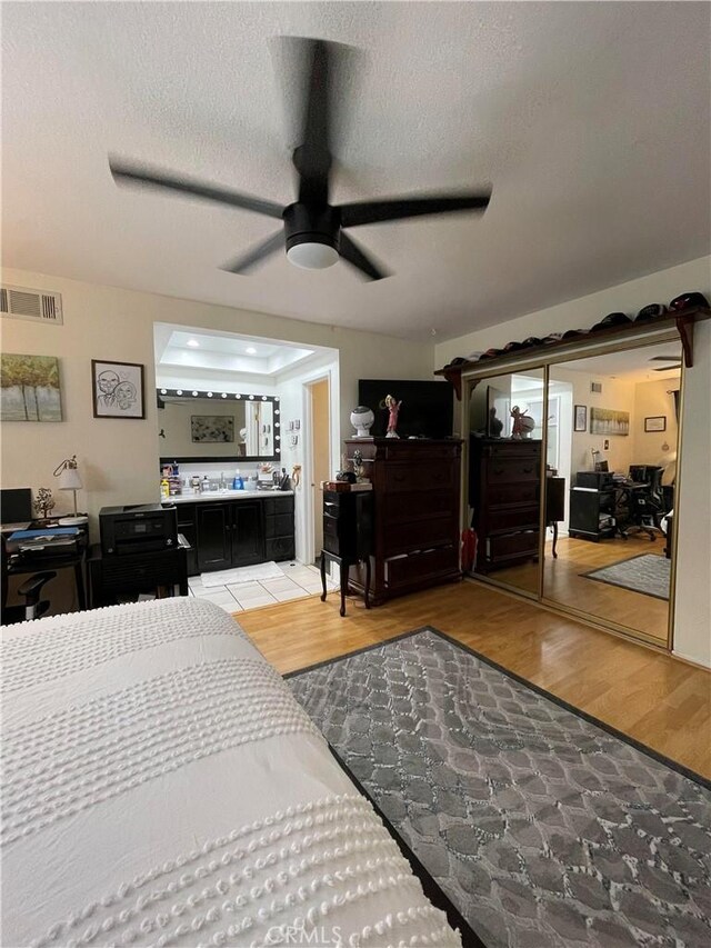 bedroom with a textured ceiling, wood-type flooring, and ceiling fan