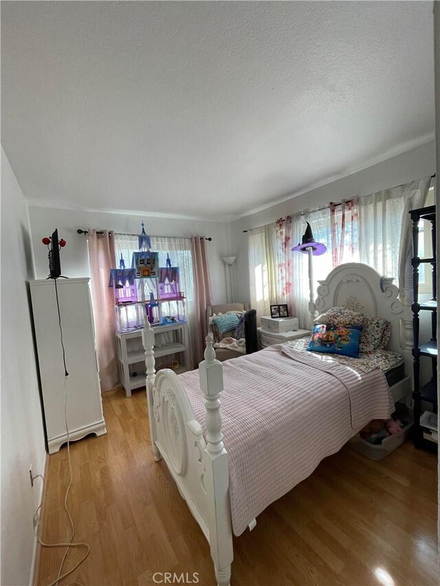 bedroom featuring multiple windows, a textured ceiling, and light hardwood / wood-style flooring