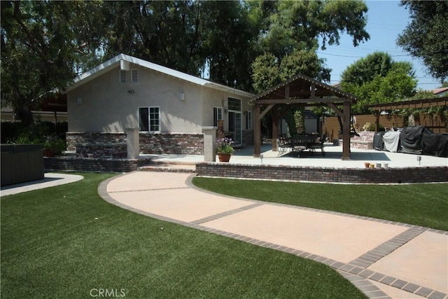 back of house with brick siding, a yard, a gazebo, and stucco siding