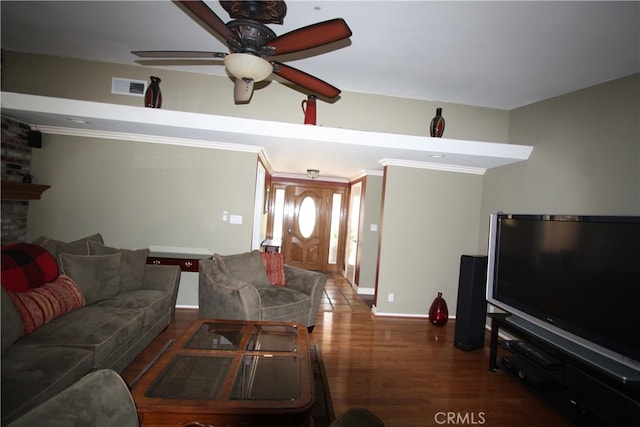 living room with ceiling fan, crown molding, dark wood-type flooring, and a large fireplace