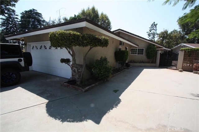 view of home's exterior featuring a garage, a gate, concrete driveway, and stucco siding