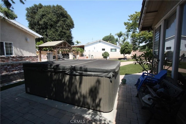 view of patio with a gazebo, fence, and a hot tub