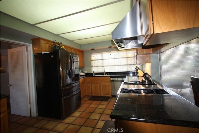 kitchen with dark countertops, range hood, stainless steel appliances, and a sink