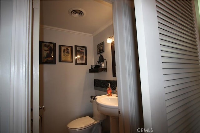 half bathroom featuring toilet, visible vents, decorative backsplash, and ornamental molding