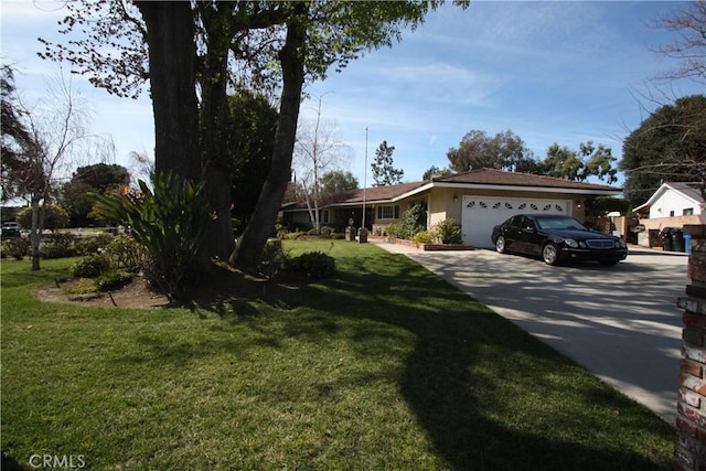 view of front of house featuring a front lawn, concrete driveway, an attached garage, and stucco siding