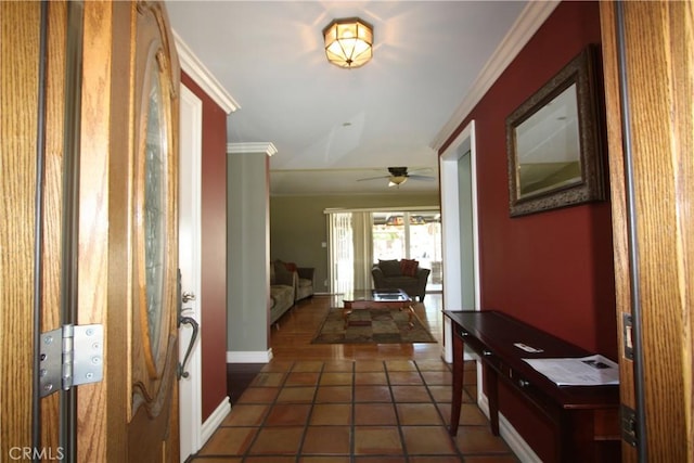 corridor with crown molding, dark tile patterned flooring, and baseboards