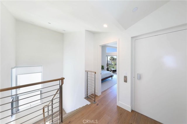 hallway with light hardwood / wood-style floors and vaulted ceiling