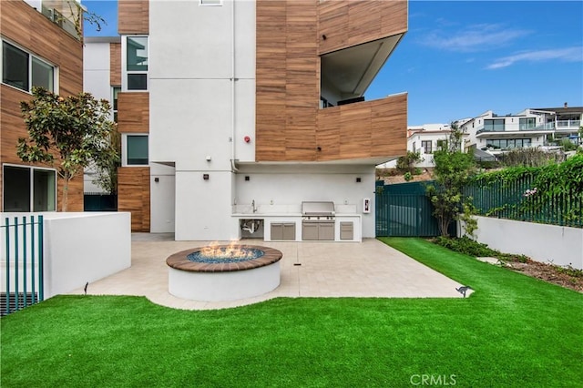 back of property with a fire pit, a lawn, sink, area for grilling, and a patio