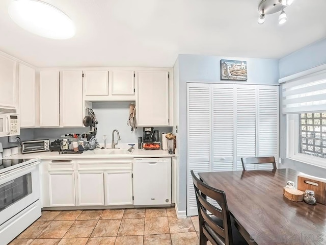 kitchen featuring white appliances, white cabinetry, light tile patterned floors, and sink